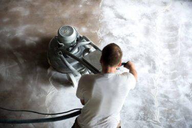 concrete floor being polished by man with machine